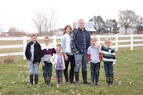 Mel's Family standing in front of a white fence