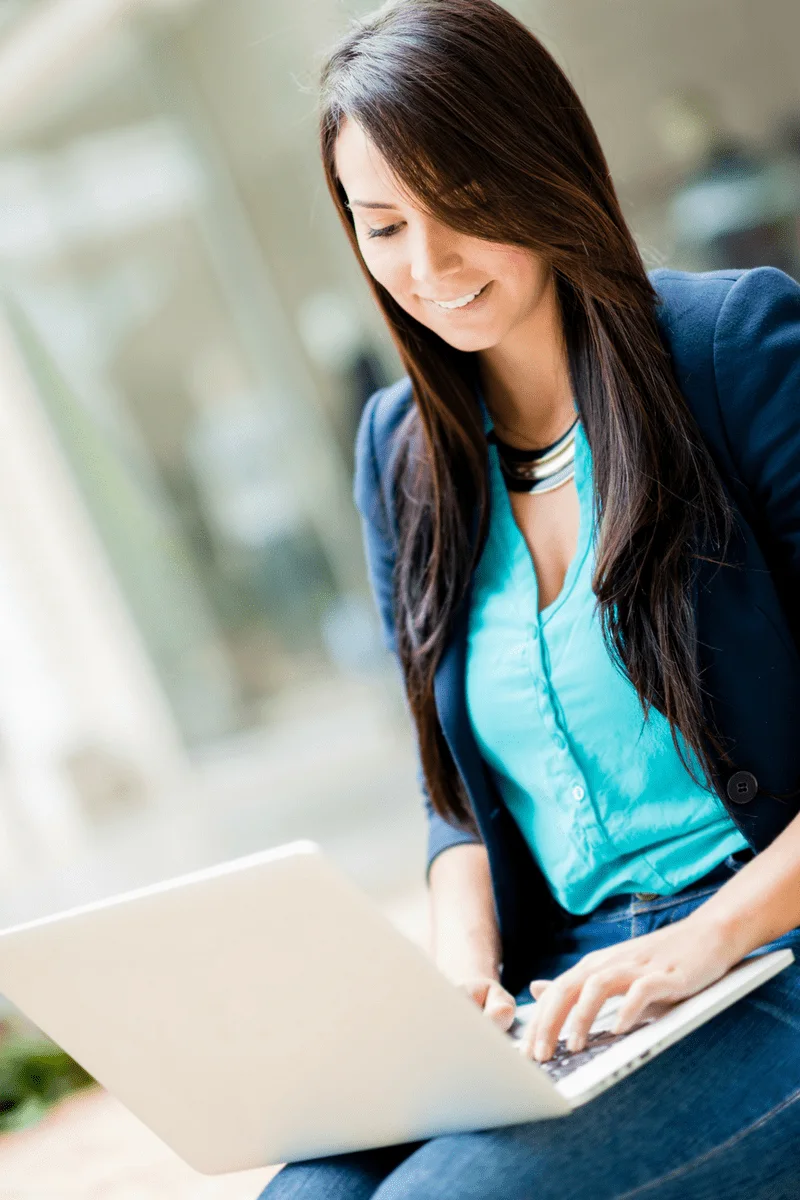 A woman sits with a laptop computer in her lap.