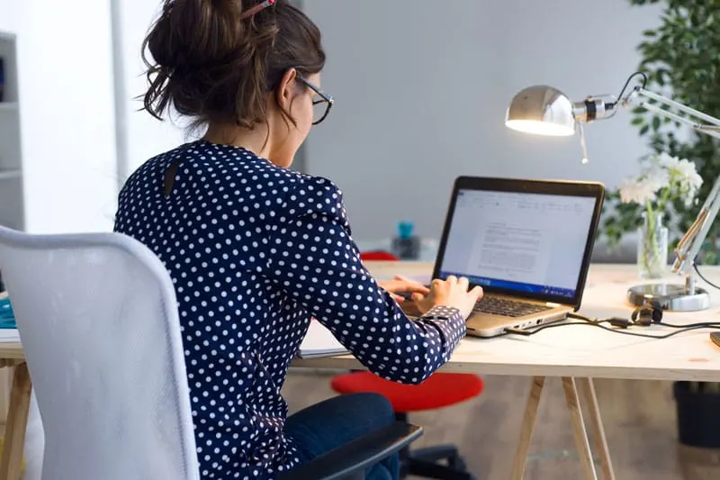 woman sitting at a desk typing on a laptop