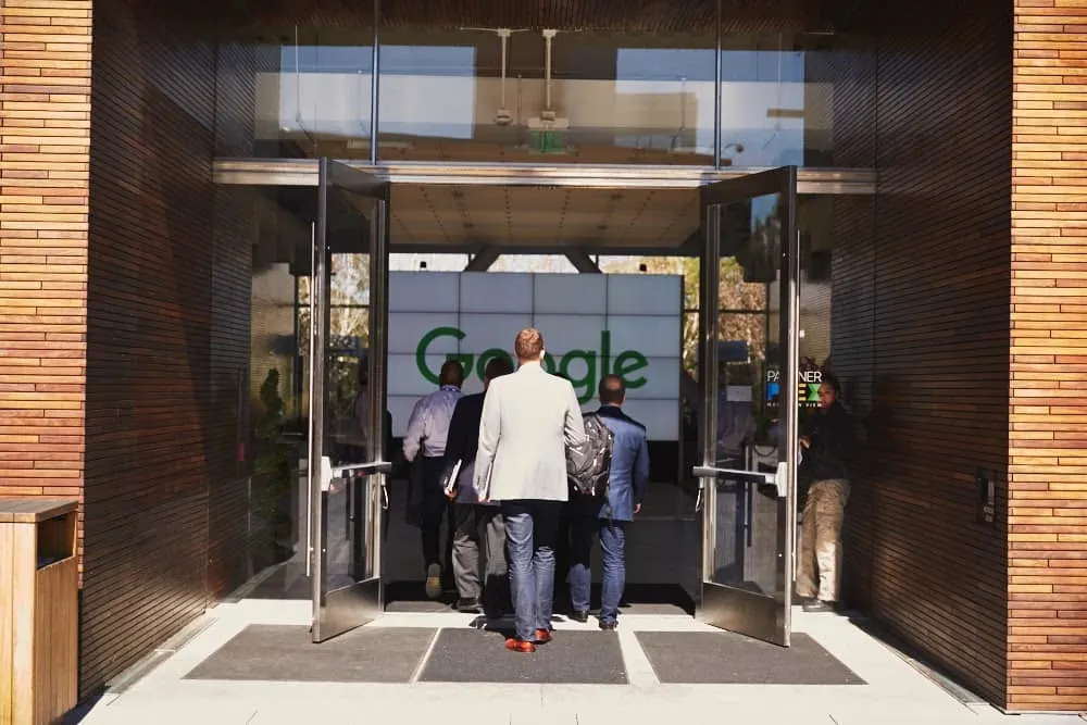 A group of men in suits entering a Google building.