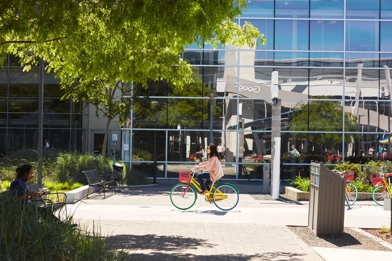 A woman rides a Google Bike on the Google Mountain View, CA campus.