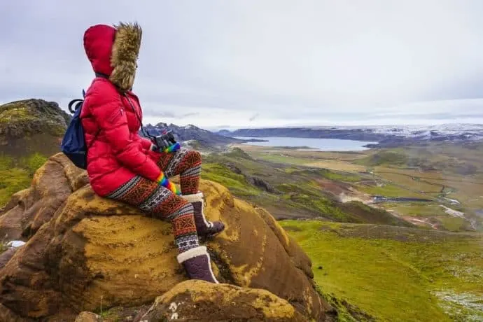 Kristin Addis looks out over a low prairie, wearing a parka and warm boots.