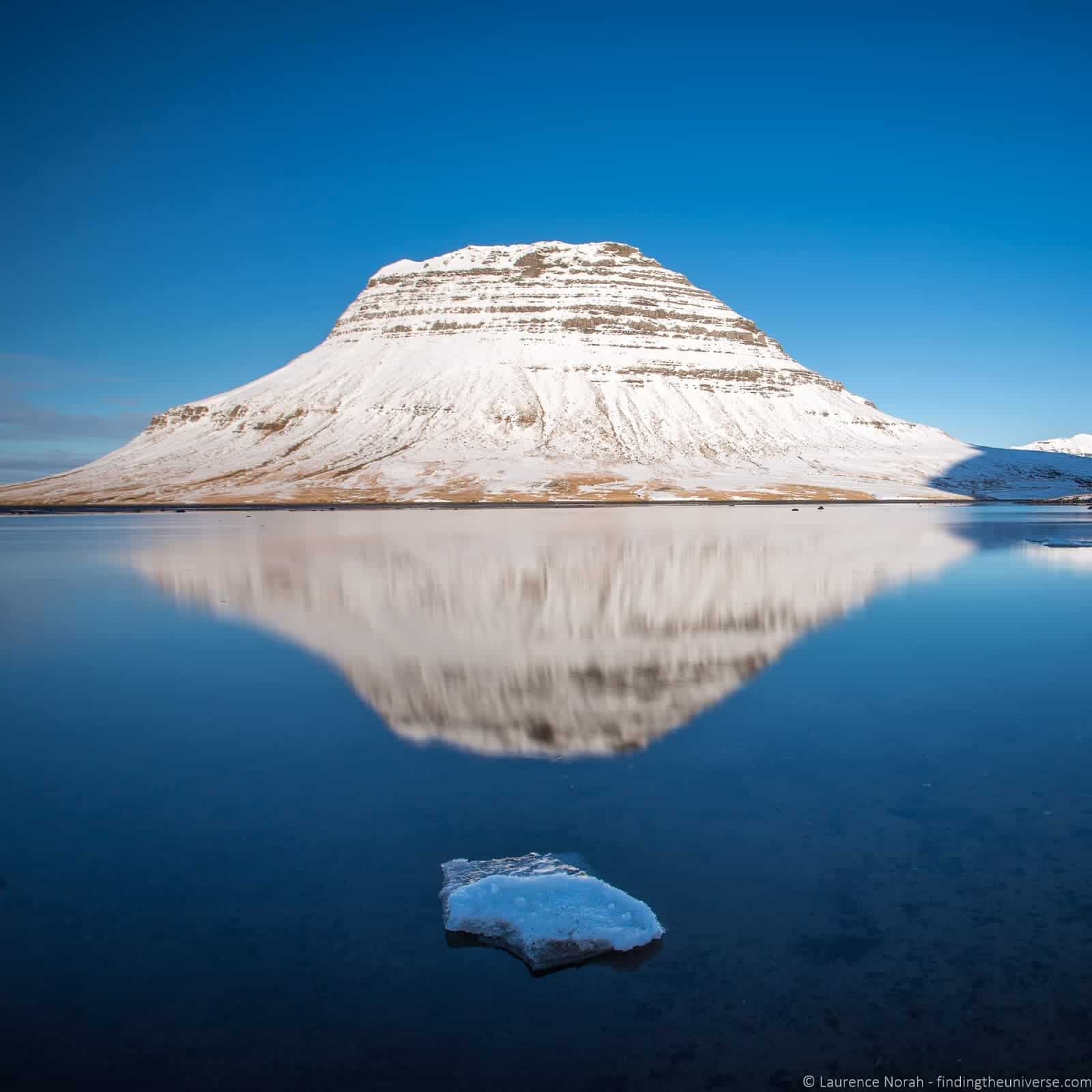 Kirkjufell in Iceland, with reflection in the icy lake at its base.