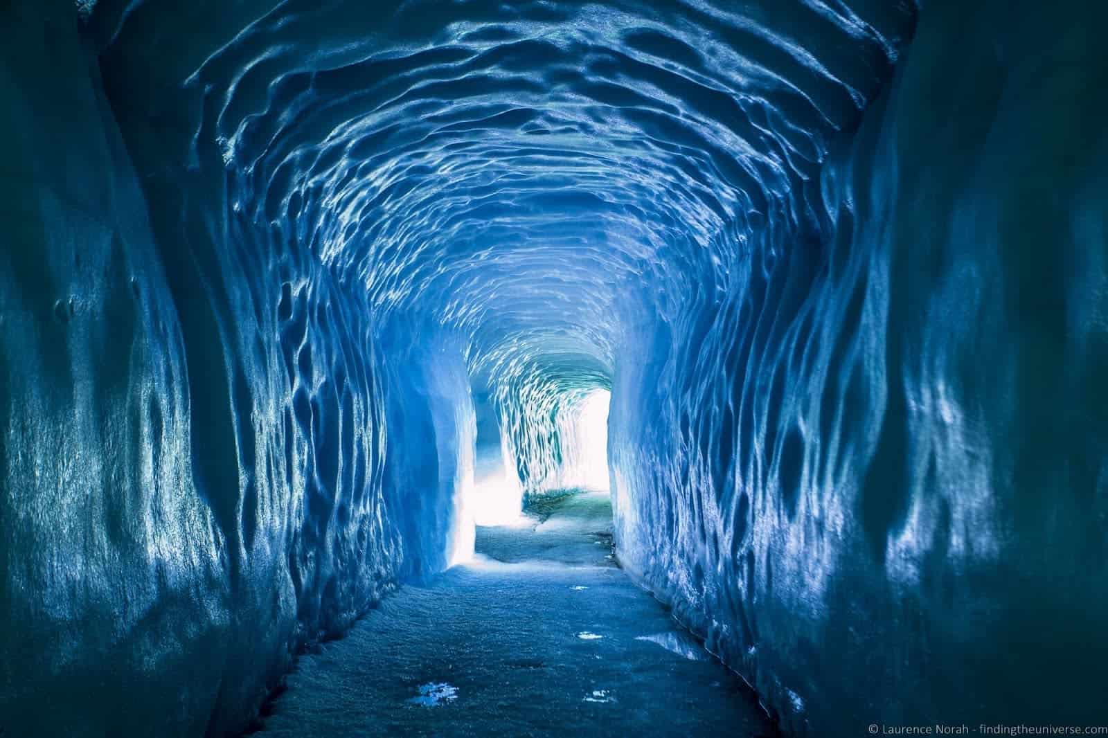 A path cuts its way through a glacier, creating an arched tunnel through the ice.