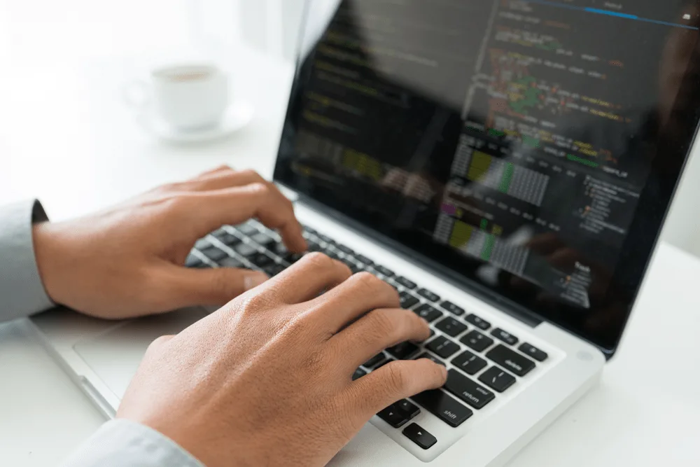 A man types on a laptop computer.