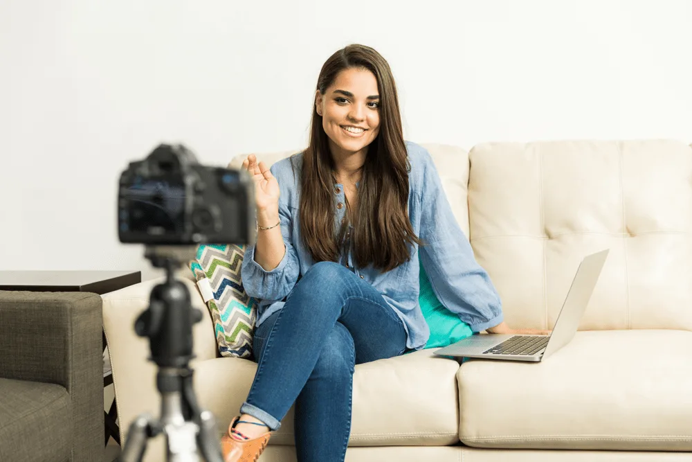 A woman vlogging on a cream leather couch.