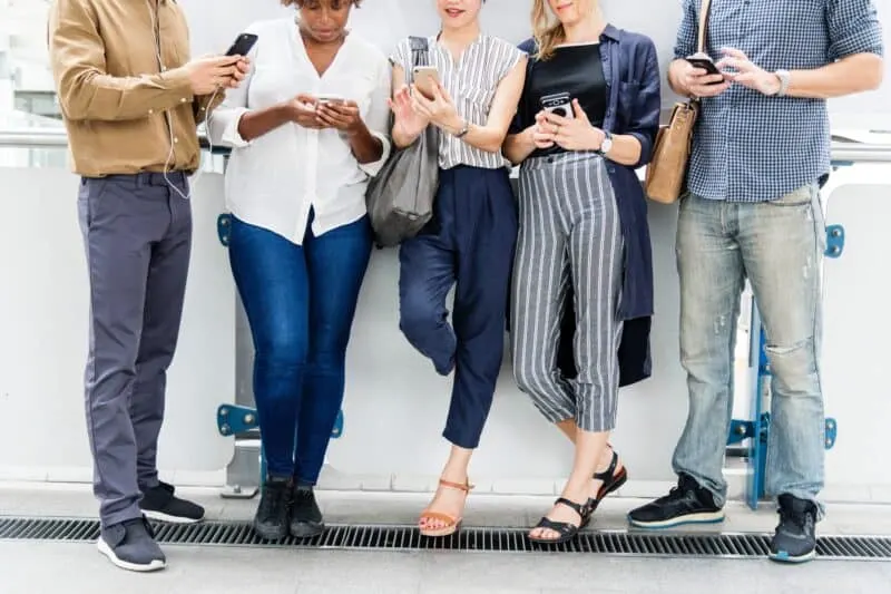 group of 5 people looking at their mobile phones