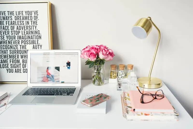 A clean desktop with open laptop computer, small stack of notebooks, and decorative items.