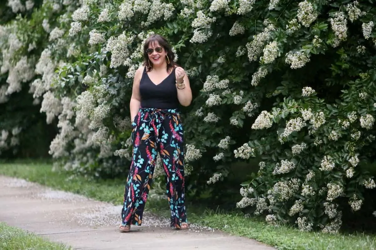 Alison Gary from Wardrobe Oxygen standing in front of flowery bushes