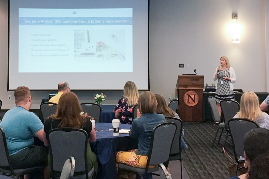 Jenny presenting in front of grouped tables.