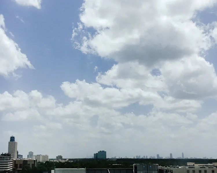 The Houston, Texas city skyline, beneath partly cloudy blue skies.