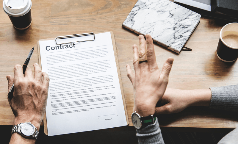 Two individuals conversing over a contract on a tabletop.