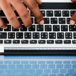 above-view of hands typing on a laptop keyboard