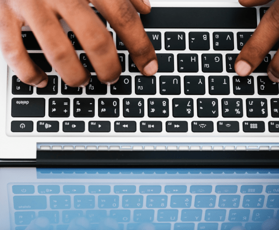 above-view of hands typing on a laptop keyboard