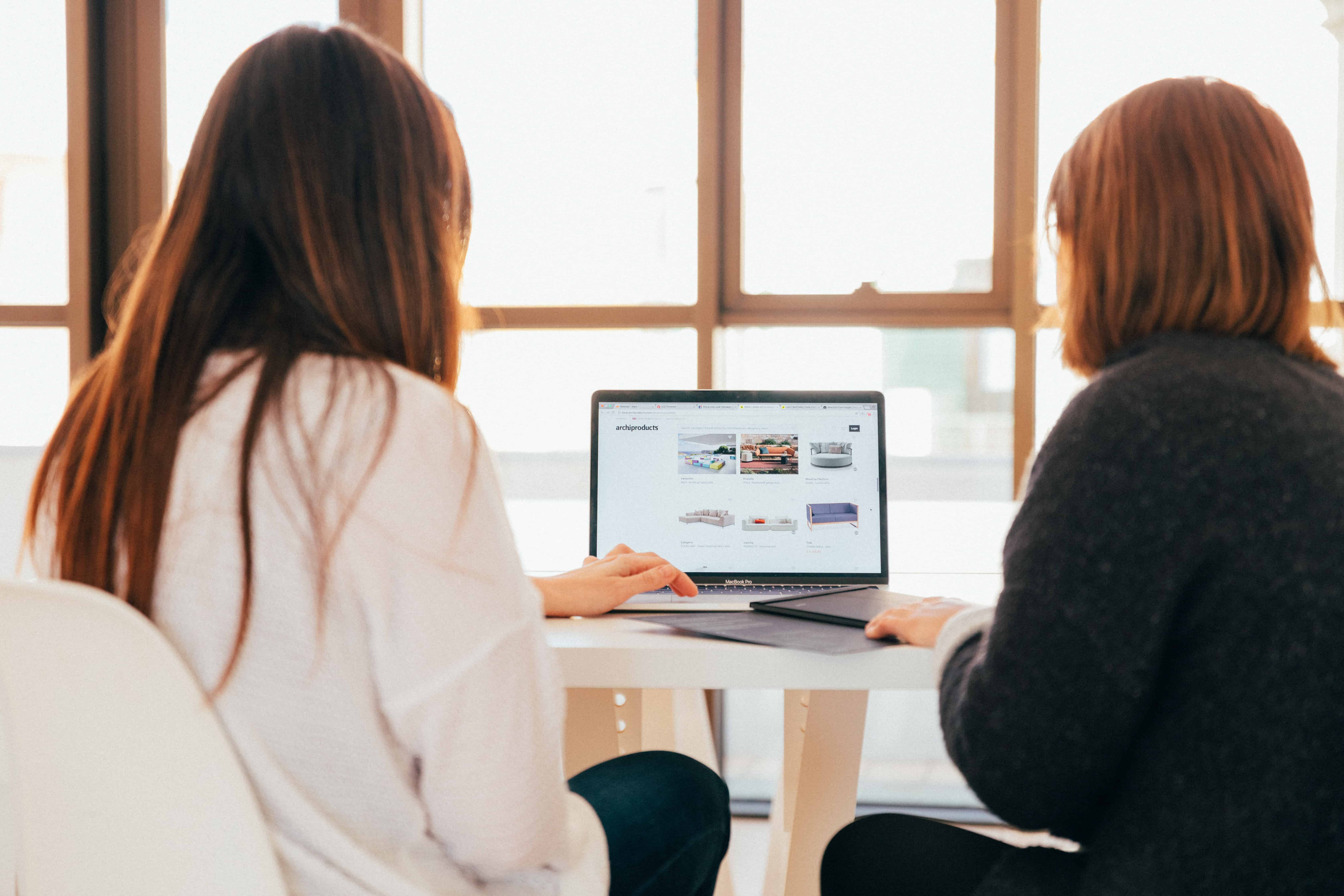 women using a computer together in an office setting