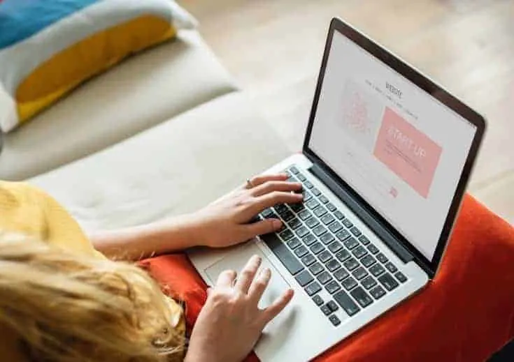 A woman sits with a laptop computer in her lap.