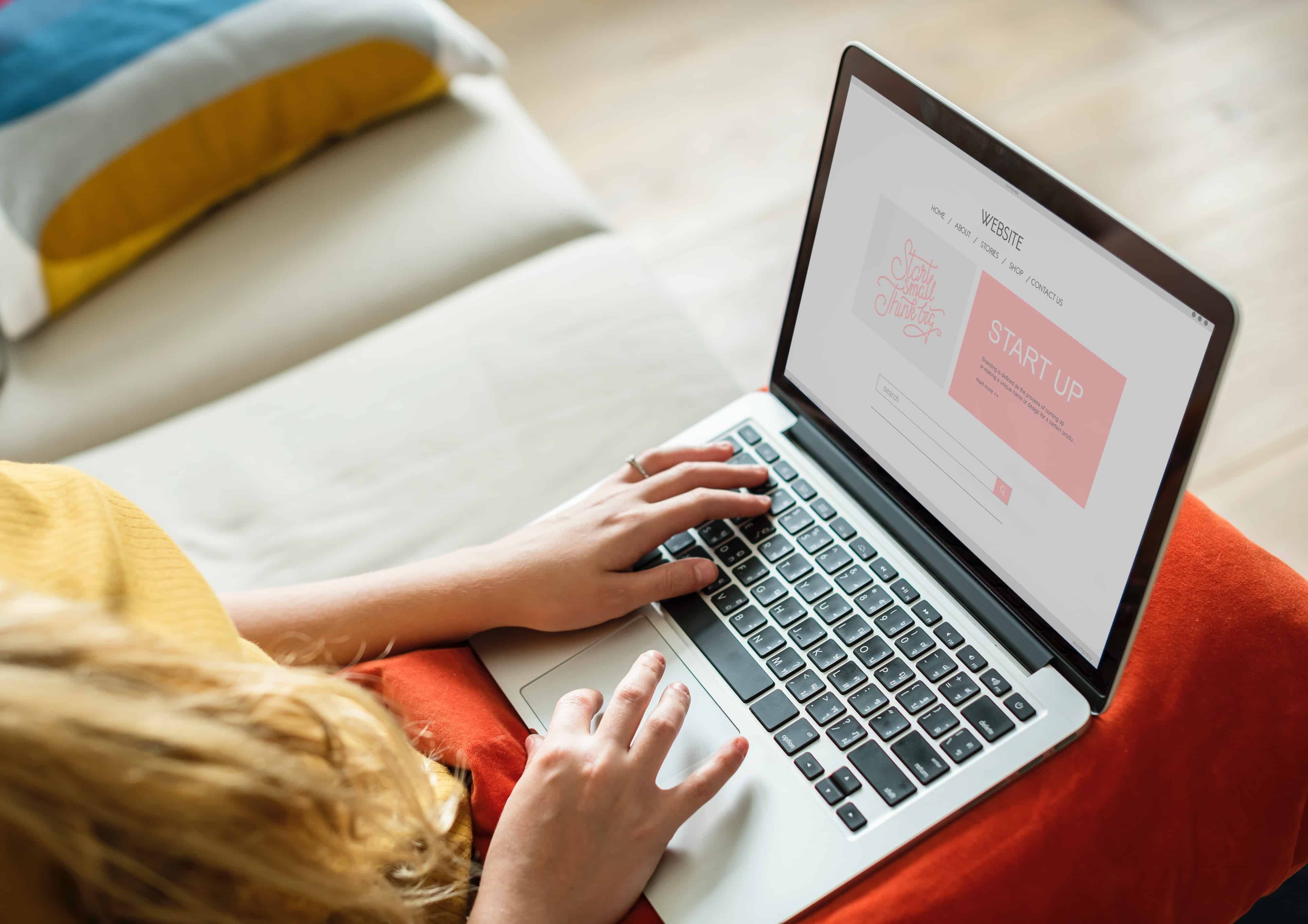 A woman using a laptop computer on her lap.