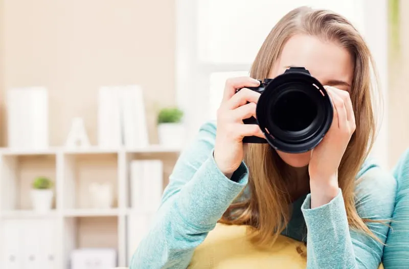 A woman looks through the viewfinder of a camera.