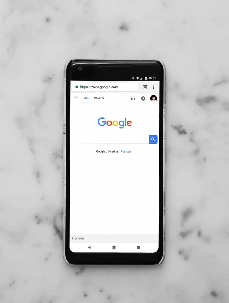 A mobile phone displaying the Google search bar home page.