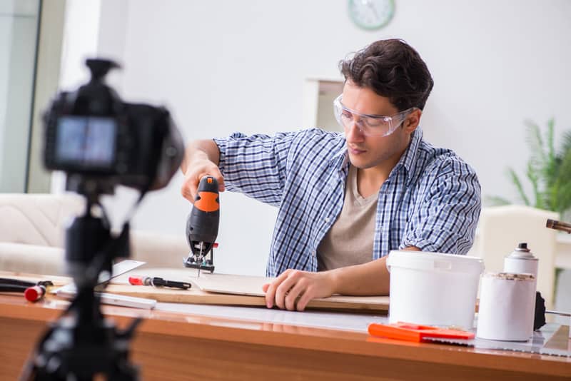 A man vlogging a DIY project, using a jig saw.