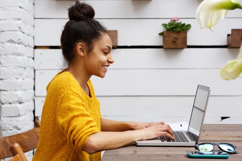 A woman sits at a table blogging.