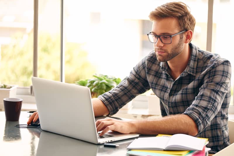 A man typing at a laptop computer.