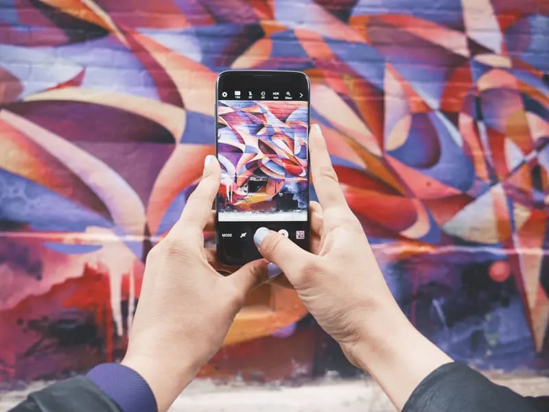 A mobile phone user taking a photograph of a mural.