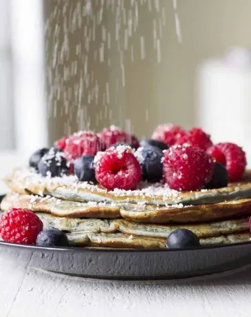 Pancakes with berries and powdered sugar.