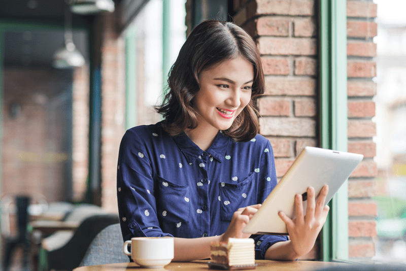 woman in a cafe with a cup of coffee and using a tablet