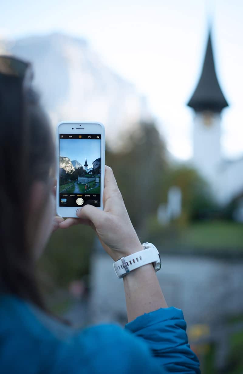 A woman takes a photograph on a smart phone.