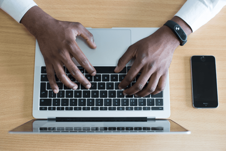 A man's hands typing on a laptop computer.