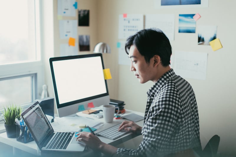 A man using laptop and desktop computers.