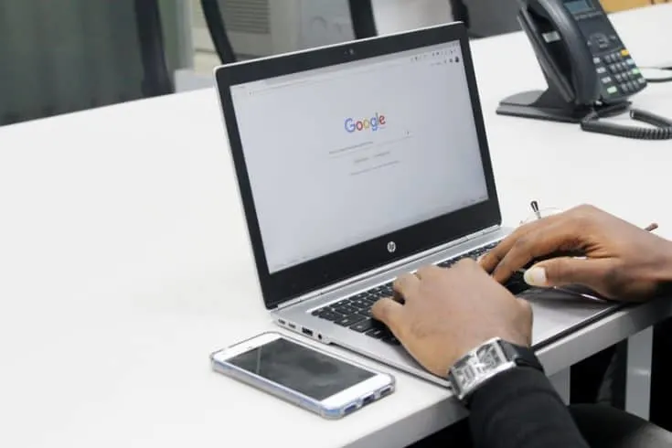 A man's hands typing on a laptop computer.