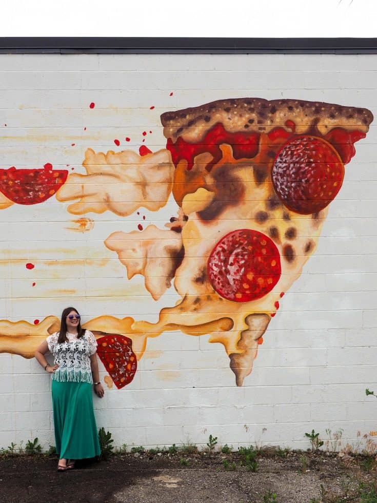 Amanda Williams in front of a mural of pizza.