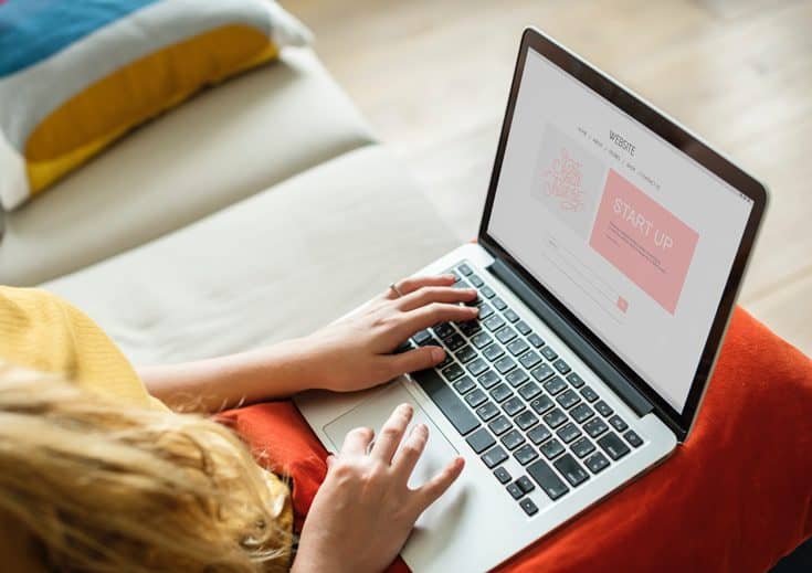 A woman sits with a laptop computer in her lap.