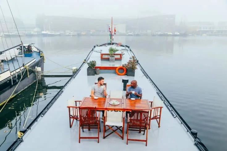 Yaya and Lloyd sitting at a dining table atop a boat.