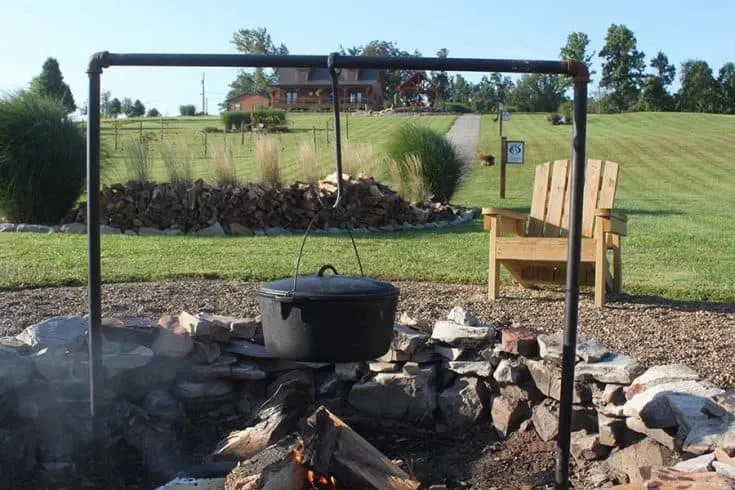 A cooking plot over a campfire, and a lawn chair.