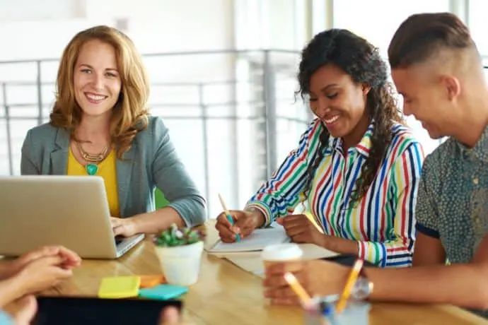 three coworkers sitting at a table smiling