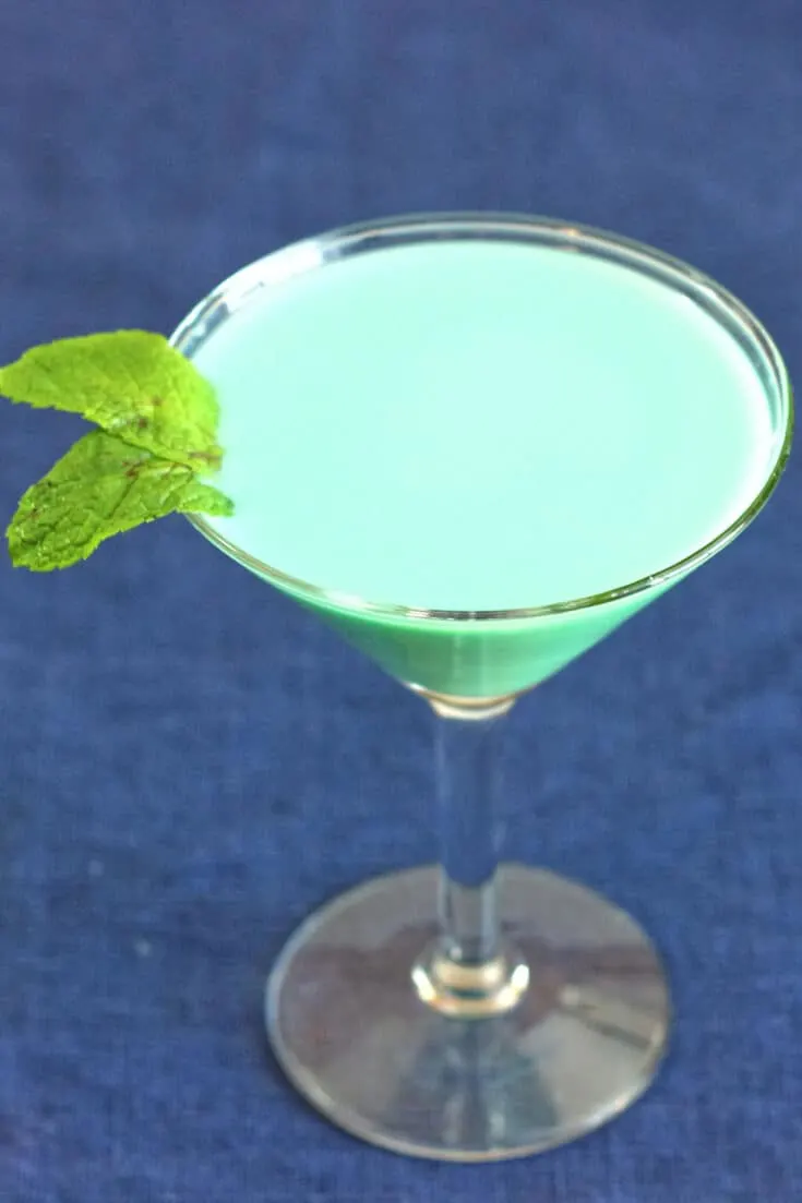 A mint green opaque cocktail, garnished with mint leaves.