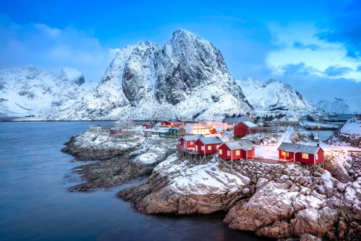 A small town on the rocky coast, with a glacier in the background.