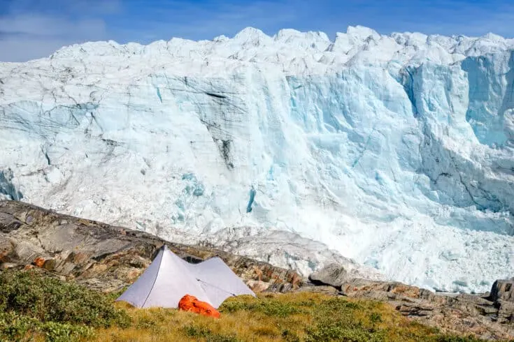 A tent set up on the mountains, overlooking a glacier.