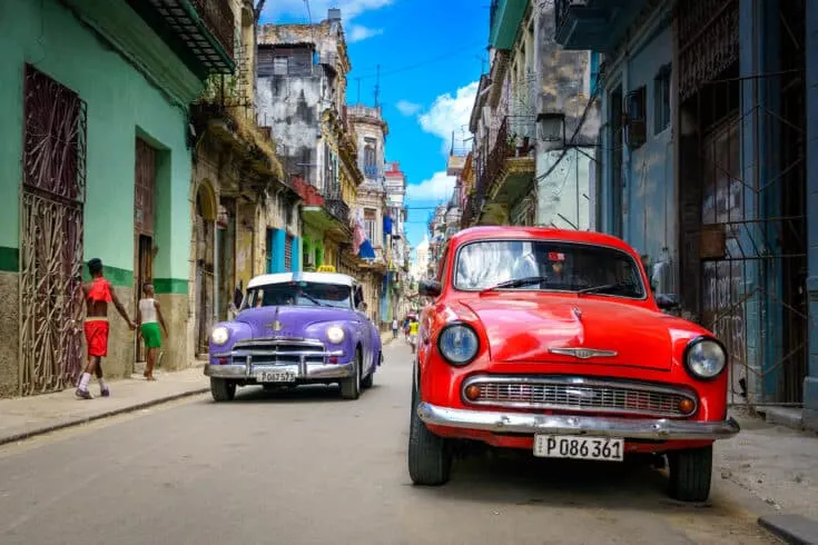 Colorful classic cars in a narrow road.