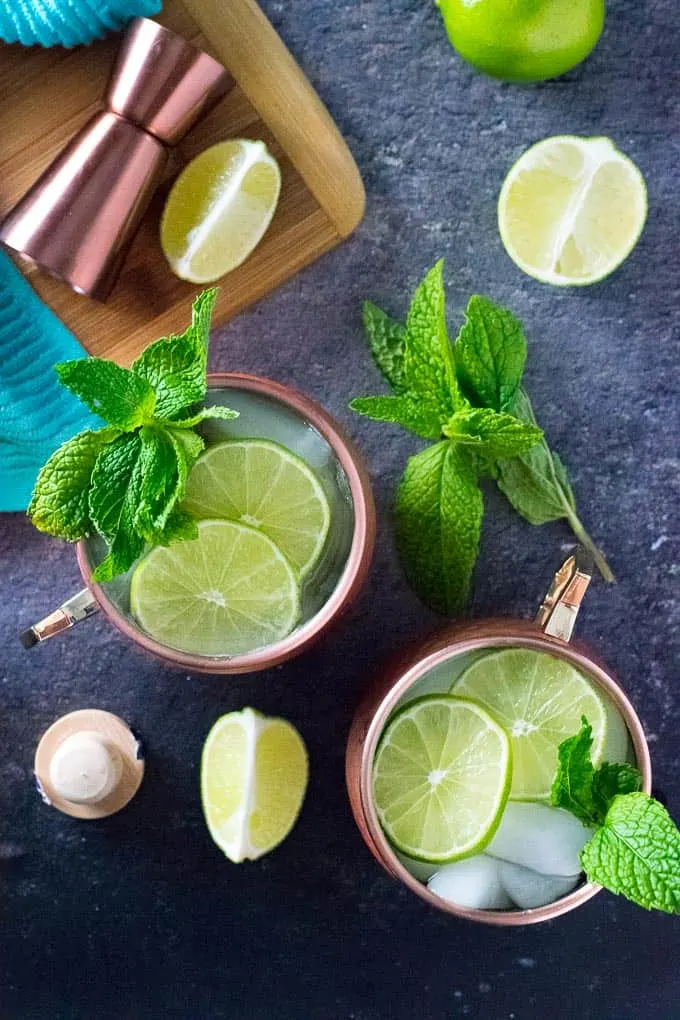 Gin moscow mules in copper tumblers, garnished with lime and mint.