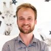 james standing in front of white wall with pictures of animals