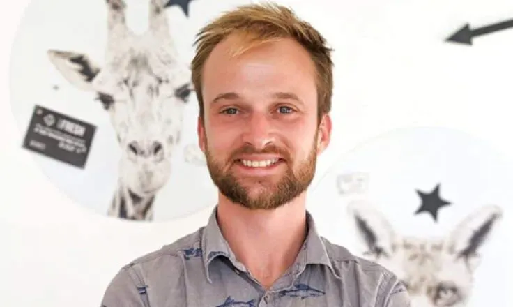 james standing in front of white wall with pictures of animals