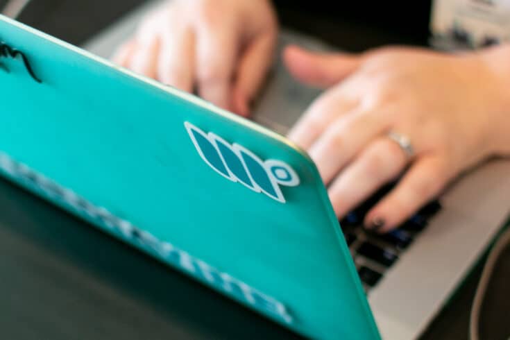 hands typing on a laptop with a mediavine sticker