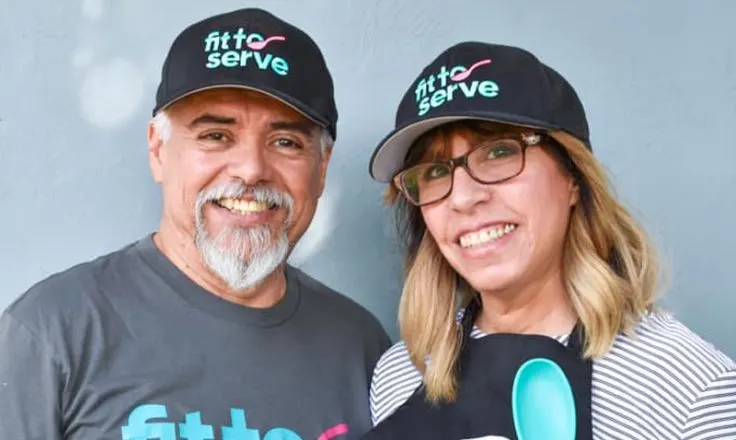 Hilda and partner wearing fit to serve shirts and hats