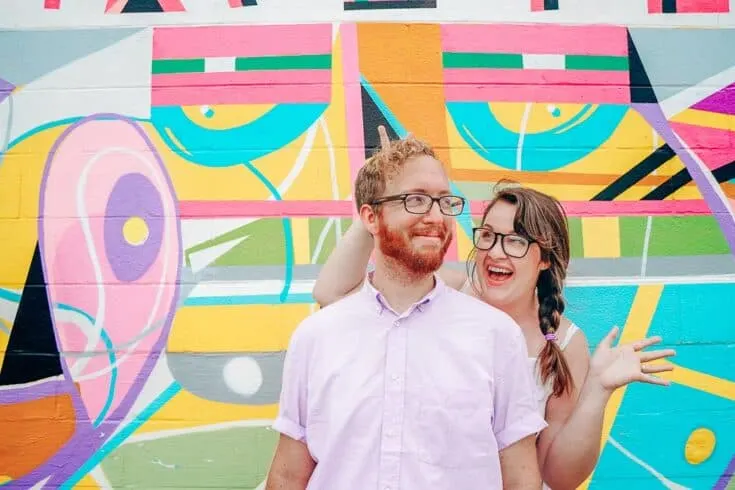 Lia Garcia and her husband stand in front of a colorful mural.