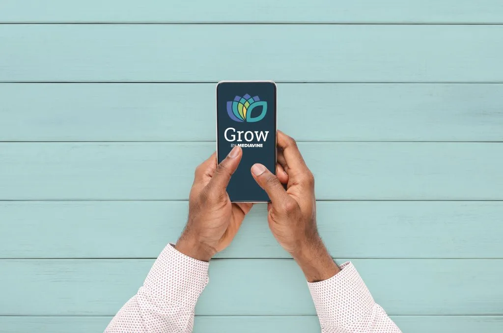 male hands using a phone displaying the grow by mediavine logo on a blue background