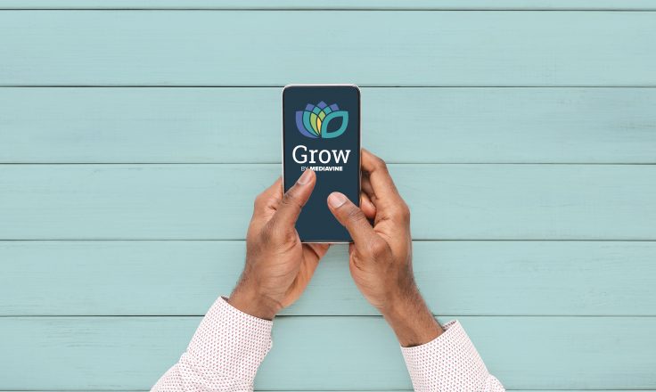 male hands using a phone displaying the grow by mediavine logo on a blue background